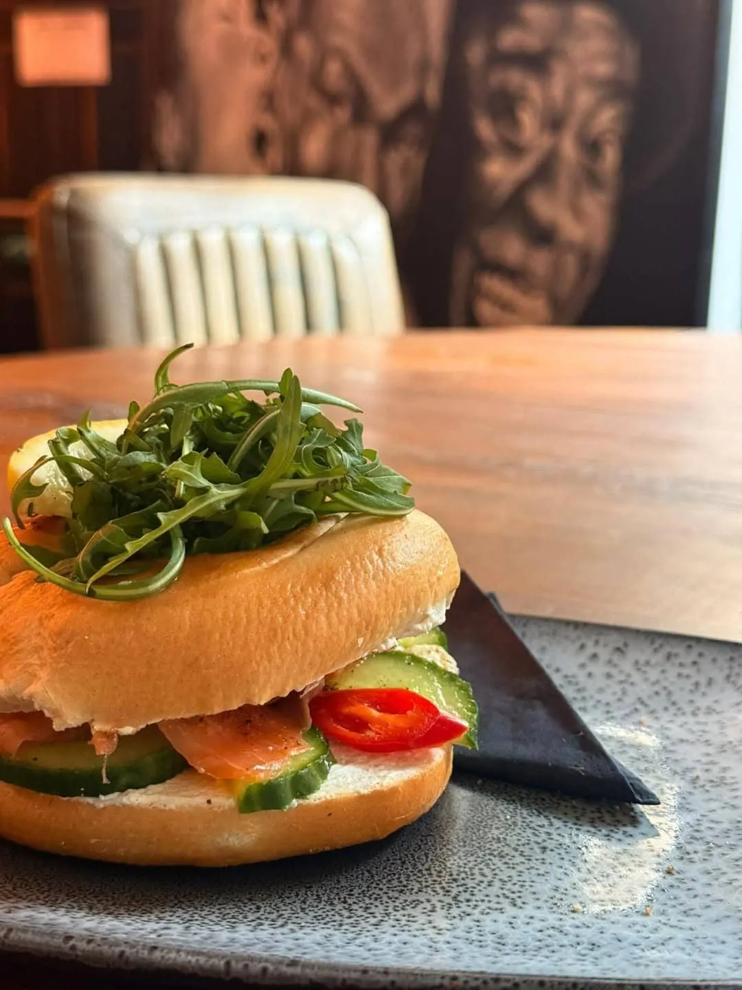 A smoked salmon bagel with salad, served on a slate plate in the coffee lounge.