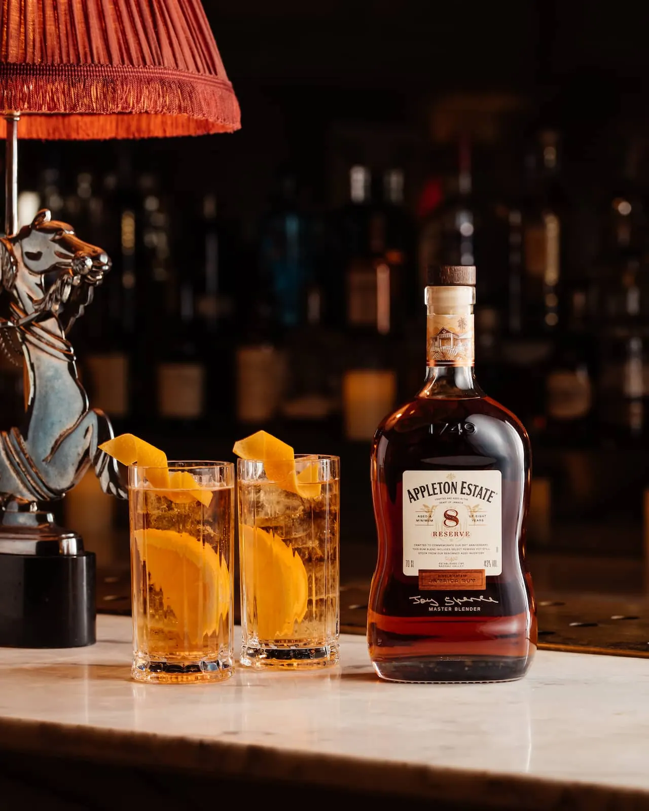 A bottle of aged Caribbean rum and two cocktails on the bar at Bankside & Co.