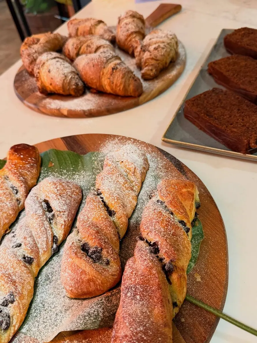 Freshly baked pastries and seasoned rolls dusted with sugar, set out on plates.