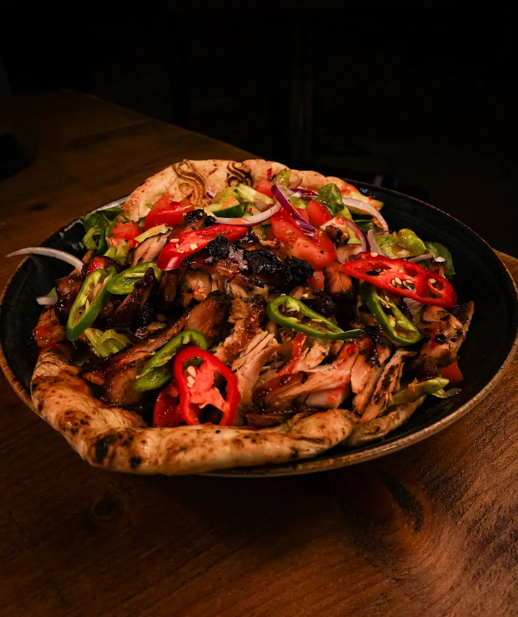 A sizzling skillet of marinated meat with peppers and onions.